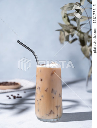 Iced coffee latte in a tall glass with milk on a light background with coffee beans, branch  118177845