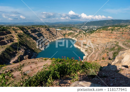 A beautiful lake surrounded by mountains and a rocky shore. The water is calm and clear, reflecting the blue sky above. The scene is serene and peaceful. A beautiful lake surrounded by mountains and a rocky shore. The water is calm and clear, reflecting the blue sky above. The scene is serene and peaceful. 118177941
