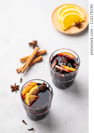 Mulled wine with orange, apple and cinnamon in glasses on a light background. Mulled wine with orange, apple and cinnamon in glasses on a light background. 118178290