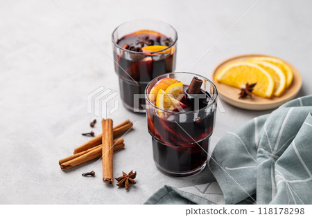 Mulled wine with orange, apple and cinnamon in glasses on a light background. Mulled wine with orange, apple and cinnamon in glasses on a light background. 118178298