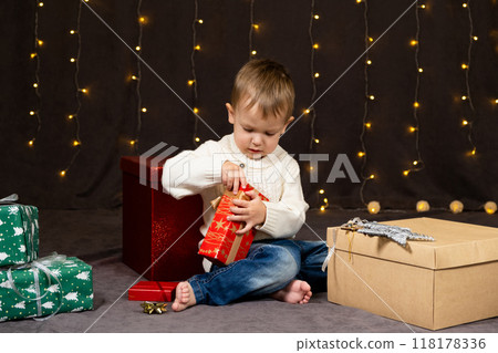 Little two-year-old boy opens Christmas gifts at home 118178336