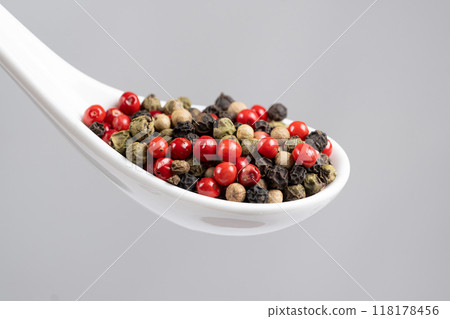 Different varieties of peppercorns, red, green, black and white peppers in a spoon 118178456
