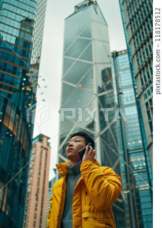 Urban professional in yellow jacket on phone in modern cityscape 118178512