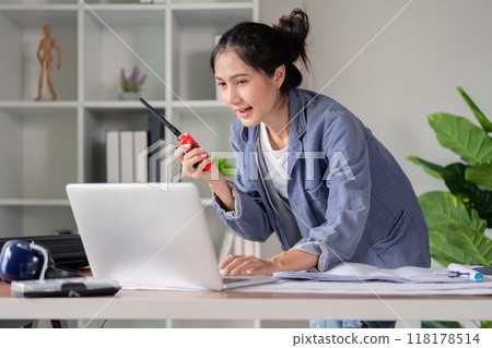 Engineer coordinating project via walkie talkie and laptop 118178514