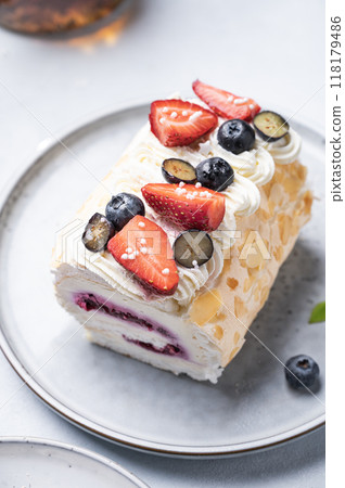 Meringue roll with almond petals, cream, jam and fresh berries close up.  118179486