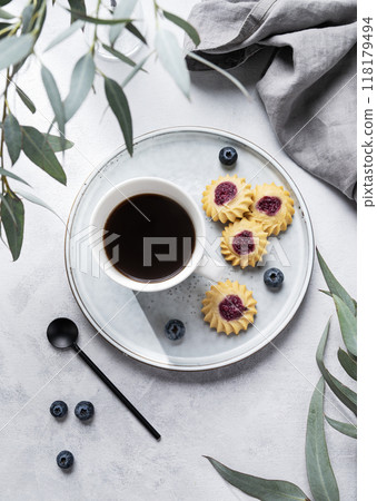 Black coffee espresso in a cup with homemade berry cookies and blueberries on a light background  118179494
