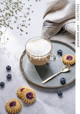 Cappuccino or latte with milk foam in a cup with homemade berry cookies and blueberries  118179501