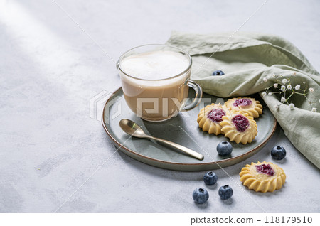 Cappuccino or latte with milk foam in a cup with homemade berry cookies and blueberries  118179510