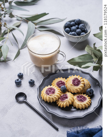 Cappuccino or latte with milk foam in a cup with homemade berry cookies in a dark plate Cappuccino or latte with milk foam in a cup with homemade berry cookies in a dark plate 118179524