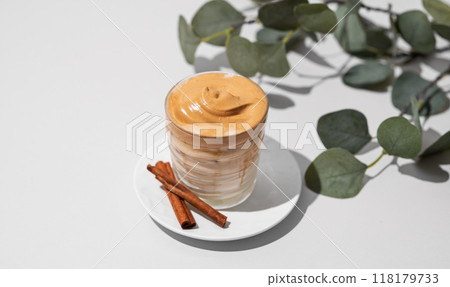 Dalgona coffee. Whipped instant iced coffee with milk in a glass with cinnamon sticks 118179733