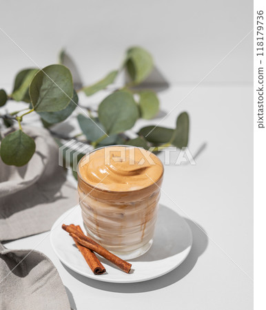 Dalgona coffee. Whipped instant iced coffee with milk in a glass with cinnamon sticks Dalgona coffee. Whipped instant iced coffee with milk in a glass with cinnamon sticks 118179736