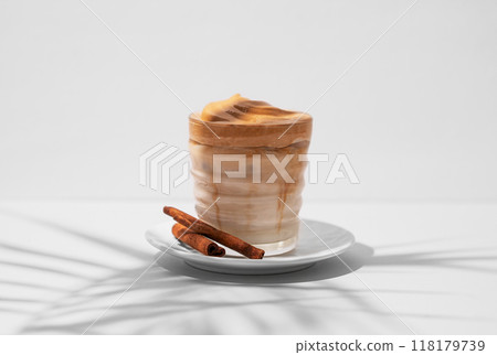 Dalgona coffee. Whipped instant iced coffee with milk in a glass with cinnamon sticks Dalgona coffee. Whipped instant iced coffee with milk in a glass with cinnamon sticks 118179739