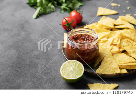 Nachos or tortilla with spicy tomato sauce on a plate with fresh vegetables and herbs  118179740