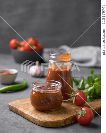 Tomato paste of hot pepper marinara with garlic, tomatoes and herbs in jars on a wooden board Tomato paste of hot pepper marinara with garlic, tomatoes and herbs in jars on a wooden board 118179742