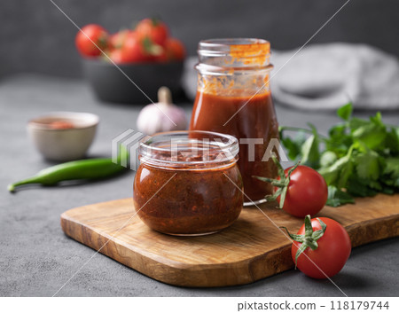 Tomato paste of hot pepper marinara with garlic, tomatoes and herbs in jars on a wooden board Tomato paste of hot pepper marinara with garlic, tomatoes and herbs in jars on a wooden board 118179744