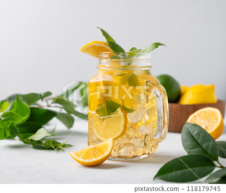 Lemonade drink or cold tea with fresh lemon, mint and ice in jar. Refreshing citrus mojito cocktail Lemonade drink or cold tea with fresh lemon, mint and ice in jar. Refreshing citrus mojito cocktail 118179745