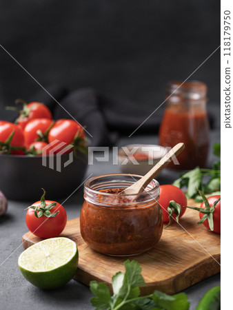 Sauce paste harissa with pepper and tomato in a jar on a dark background with fresh vegetables Sauce paste harissa with pepper and tomato in a jar on a dark background with fresh vegetables 118179750