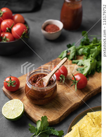 Sauce paste harissa with pepper and tomato in a jar on a dark background with fresh vegetables Sauce paste harissa with pepper and tomato in a jar on a dark background with fresh vegetables 118179752