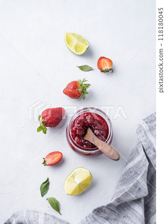 Strawberry jam in a jar on a light background with fresh berries.  118180045