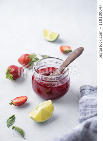 Strawberry jam in a jar on a light background with fresh berries. Strawberry jam in a jar on a light background with fresh berries. 118180047