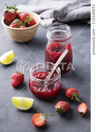 Two jars of strawberry jam on a dark background with fresh berries. Homemade sweets. 118180053