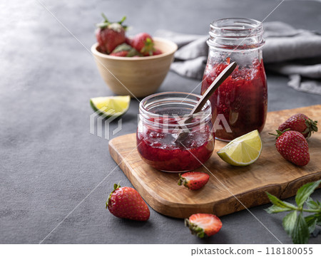 Two jars of strawberry jam on a wooden board on a dark background with fresh berries Two jars of strawberry jam on a wooden board on a dark background with fresh berries 118180055