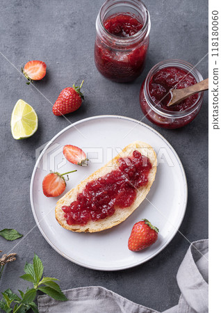 Strawberry jam on a piece of bread on a plate on a dark background with fresh berries and jar Strawberry jam on a piece of bread on a plate on a dark background with fresh berries and jar 118180060