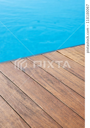 Empty wooden tabletop in front of a swimming pool with blue tiles. Empty wooden tabletop in front of a swimming pool with blue tiles. 118180067