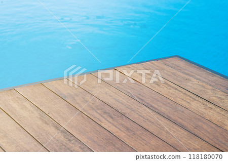 Empty wooden tabletop in front of a swimming pool with blue tiles. Empty wooden tabletop in front of a swimming pool with blue tiles. 118180070