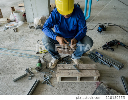 A builder works with screws and nuts on a wooden pallet 118180355