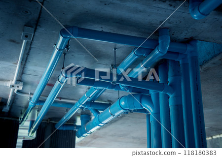A bright blue pipes attached to a solid concrete wall A bright blue pipes attached to a solid concrete wall 118180383