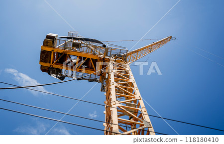 A large yellow crane stands out against a bright blue sky A large yellow crane stands out against a bright blue sky 118180410