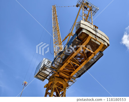 A large yellow crane stands out against a bright blue sky 118180553