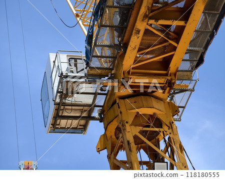 A large yellow crane stands out against a bright blue sky 118180555