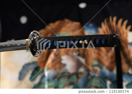 Japanese katana samurai sword hang in air over Kimono blur background. Sharp blade of katana samurai sward is weapon of japanese warrior martial art Japanese katana samurai sword hang in air over Kimono blur background. Sharp blade of katana samurai sward is weapon of japanese warrior martial art 118180574