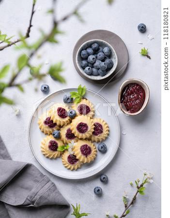 Homemade kurabye cookies with berry filling on a blue background with blueberries and jam. 118180821