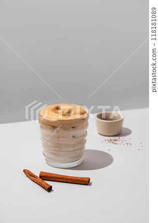 Dalgona coffee. Whipped instant iced coffee with soy milk in a glass with cinnamon sticks  118181089