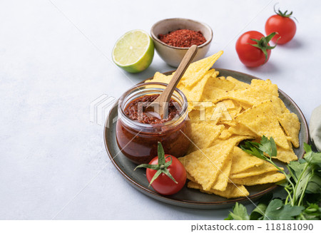 Nachos or tortilla with spicy tomato sauce on a plate with fresh vegetables and herbs  118181090