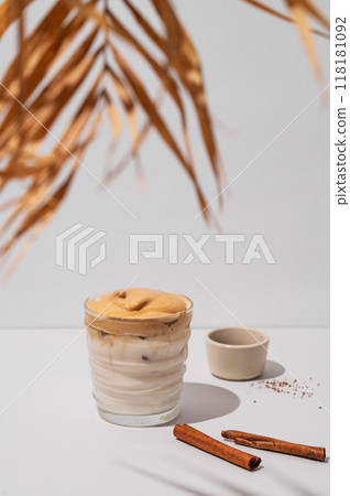Dalgona coffee. Whipped instant iced coffee with milk in a glass with cinnamon sticks Dalgona coffee. Whipped instant iced coffee with milk in a glass with cinnamon sticks 118181092