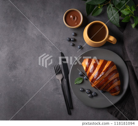 Freshly baked chocolate croissant with blueberries on a gray plate on a dark background Freshly baked chocolate croissant with blueberries on a gray plate on a dark background 118181094