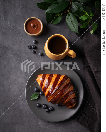 Freshly baked chocolate croissant with blueberries on a gray plate on a dark background Freshly baked chocolate croissant with blueberries on a gray plate on a dark background 118181097