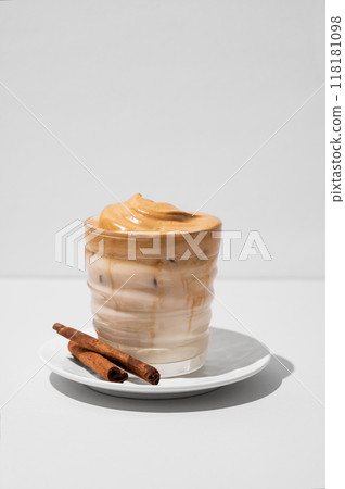 Dalgona coffee. Whipped instant iced coffee with milk in a glass with cinnamon sticks  118181098