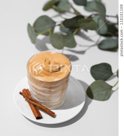 Whipped Dalgona coffee. Instant cold coffee with ice in a glass with cinnamon sticks Whipped Dalgona coffee. Instant cold coffee with ice in a glass with cinnamon sticks 118181109