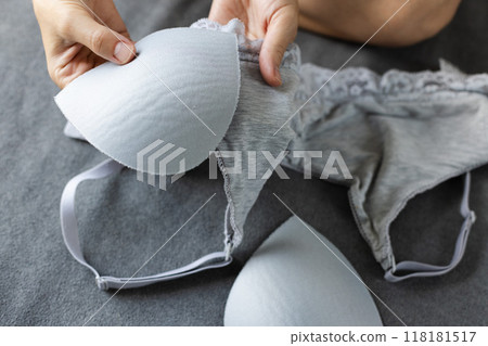 Woman puts pads in a bra for better shape of the lingerie. Grey colour cotton lingerie. 118181517