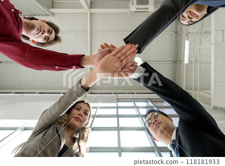 Team building concept. Coworkers standing in circle join hands together, celebrating business success in modern office with high ceiling. Bottom View Team building concept. Coworkers standing in circle join hands together, celebrating business success in modern office with high ceiling. Bottom View 118181933