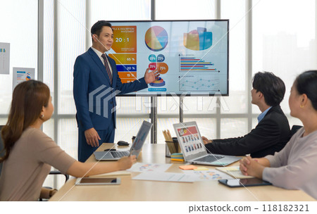 Group of business people are gathered in a meeting room, discussing and sharing ideas around a large conference table. 118182321