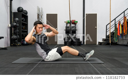 Young asian man Sit-up on exercise mat. There are dumbbell set with rack in the gym. 118182733