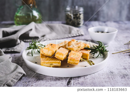 Spicy fried tofu on skewers and rosemary on a plate on the table Spicy fried tofu on skewers and rosemary on a plate on the table 118183663