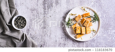 Pieces of delicious fried tofu soy cheese on skewers on a plate on the table top view web banner 118183670