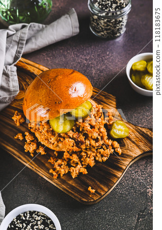 Hearty burger with ground beef and pickles on a board on a table vertical view 118183675